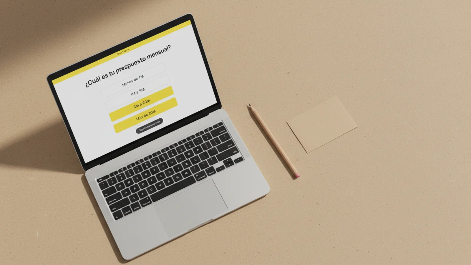 Top-down de MacBook sobre papel kraft con formulario condicional y opción amarilla seleccionada, lápiz al lado.