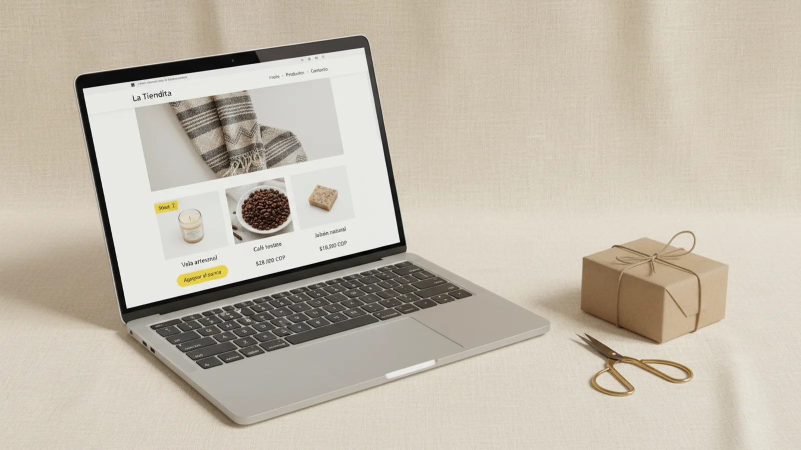 MacBook frontal close-up sobre lino crema con tienda online La Tiendita, paquete craft pequeño y tijeras de latón.
